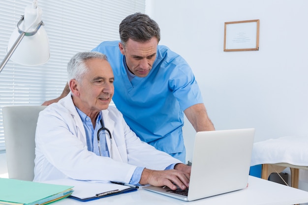 Surgeon and doctor discussing over laptop