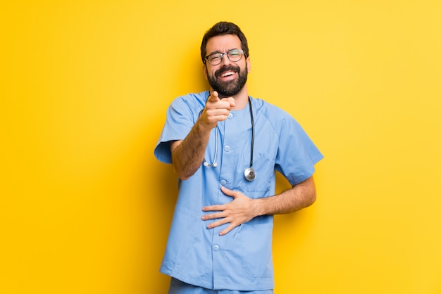 Surgeon doctor man pointing with finger at someone and laughing a lot