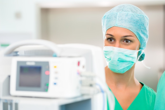 Surgeon doctor in sterile operating room or operation theater checking data on heart monitor in emergency situation