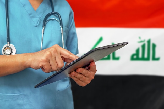 Chirurgo o medico utilizzando una tavoletta digitale sullo sfondo della bandiera dell'iraq