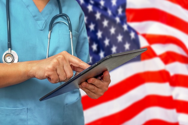 Photo surgeon or doctor using a digital tablet on the background of the usa flag