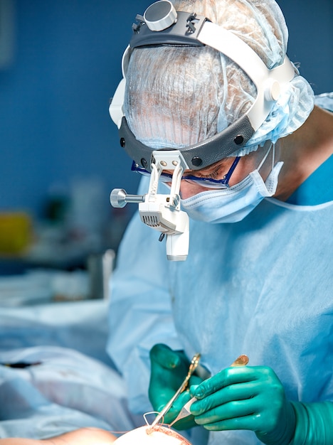 Medico chirurgo che indossa maschera protettiva e cappello durante il funzionamento
