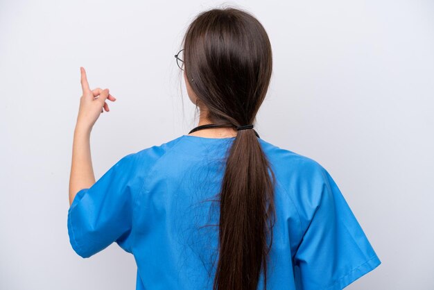 Surgeon doctor woman holding tools isolated on white background pointing back with the index finger