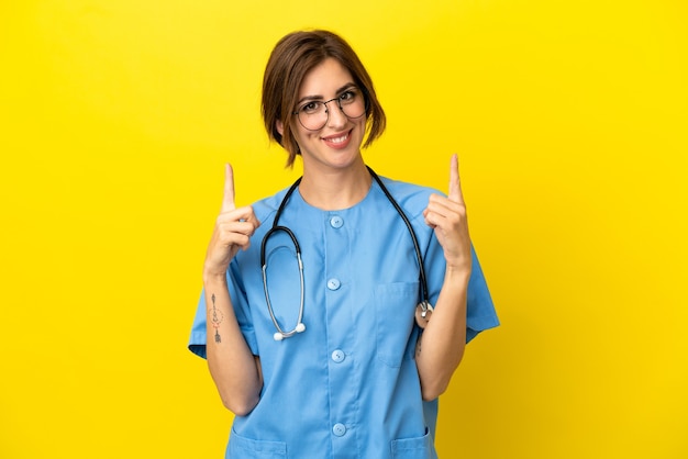 Женщина-врач-хирург изолирована на желтом фоне, указывая вверх прекрасную идею