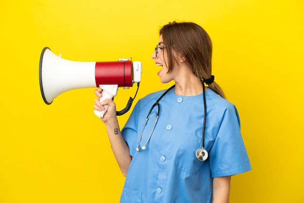 Surgeon doctor woman isolated on yellow background shouting through a megaphone