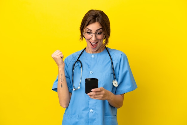 Surgeon doctor woman isolated on yellow background surprised and sending a message