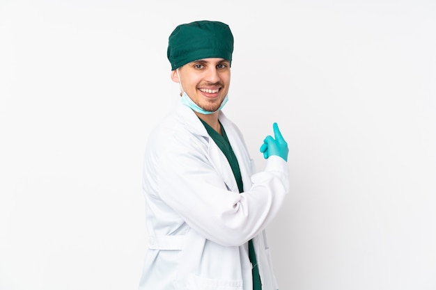 Surgeon in green uniform on white pointing back