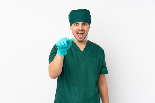 Surgeon in green uniform on white surprised and pointing front