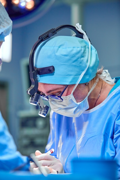 Surgeon and his assistant performing cosmetic surgery in hospital operating room.