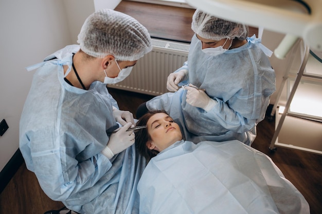 Surgeon and his assistant performing cosmetic surgery on nose in hospital operating room Nose reshaping augmentation Rhinoplasty