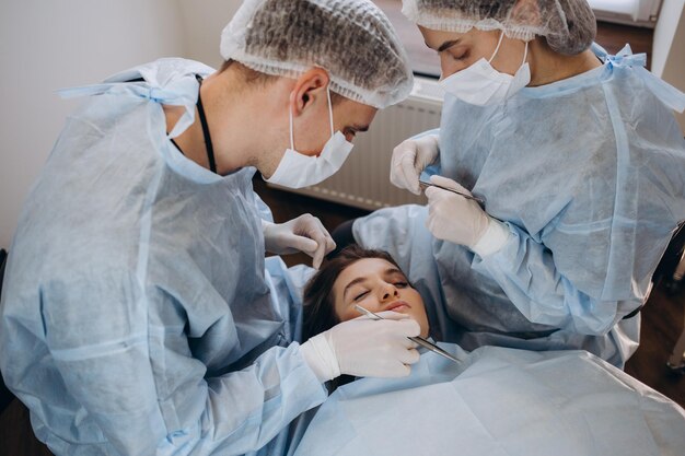 Surgeon and his assistant performing cosmetic surgery on nose\
in hospital operating room nose reshaping augmentation\
rhinoplasty