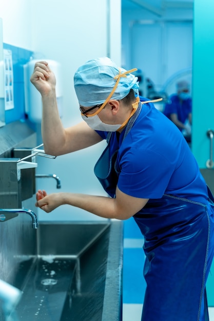 Surgeon in hospital washing hands thoroughly before performing a surgery.