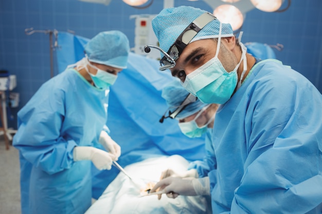 Surgeon looking at camera while colleagues performing operation