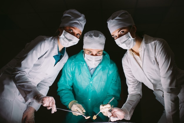 The surgeon makes an operation in a dark room.