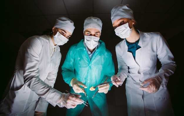 The surgeon makes an operation in a dark room.