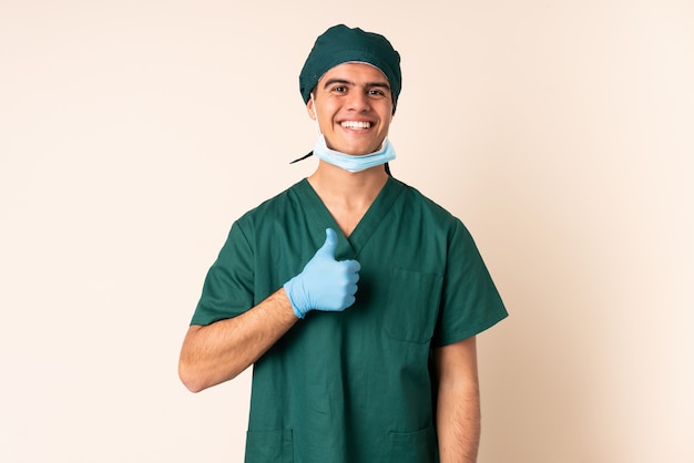 엄지 손가락 제스처를주는 격리 된 배경 위에 파란색 유니폼 외과 의사