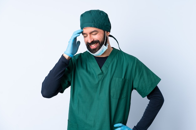 Uomo del chirurgo in uniforme verde sopra la risata isolata della parete