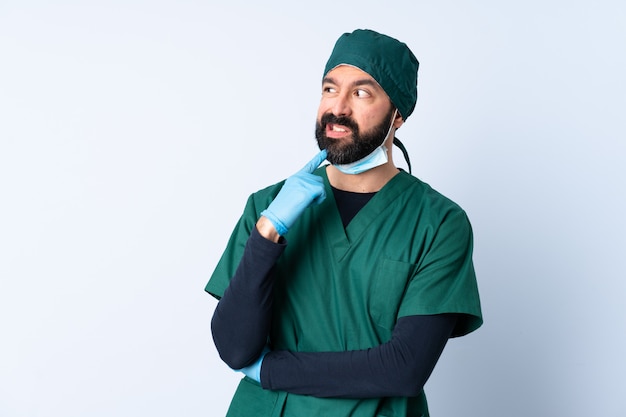 Surgeon man in green uniform over isolated wall nervous and scared