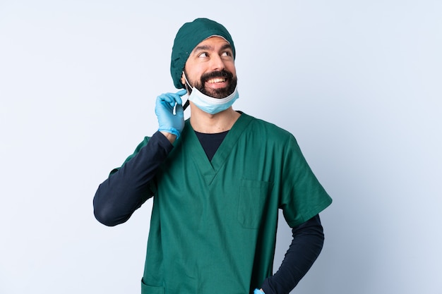 Surgeon man in green uniform over isolated wall thinking an idea