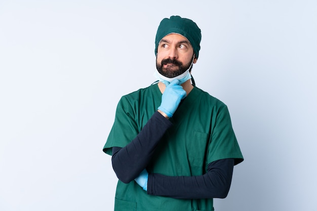 Surgeon man in green uniform over wall having doubts and thinking