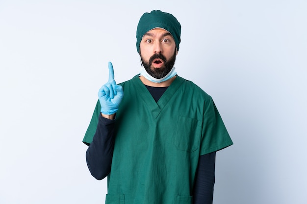 Surgeon man in green uniform over wall intending to realizes the solution while lifting a finger up