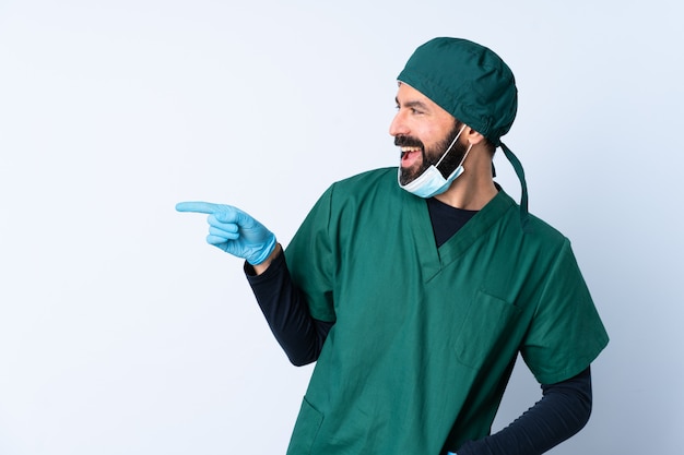 Surgeon man in green uniform over wall pointing finger to the side