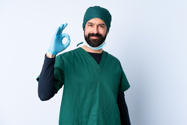 Surgeon man in green uniform over wall showing ok sign with fingers