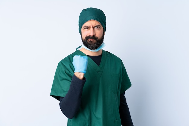 Surgeon man in green uniform over wall with unhappy expression