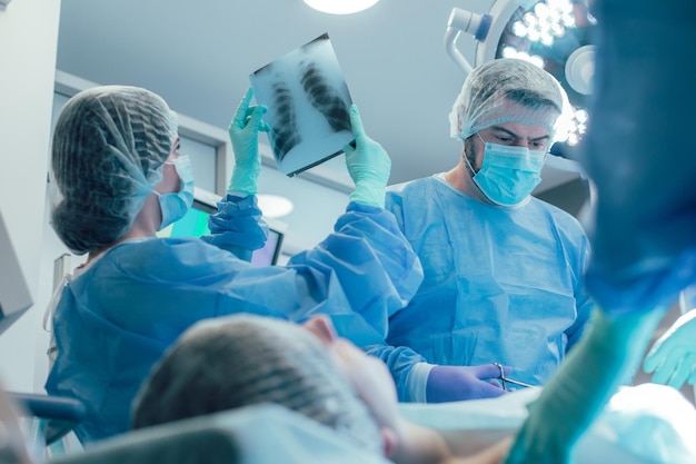 Surgeon near the patient frowning and a nurse looking at the chest x ray