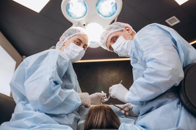 病院の手術室で乳房の美容整形を行う外科医医療処置中に外科用ループを着用したマスクの外科医乳房増強拡大の強化