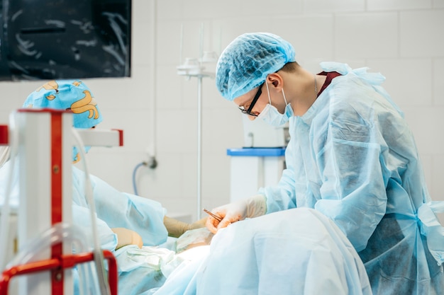 Surgeon performing surgery on breasts in hospital operating room. Surgeon in mask wearing surgical loupes during medical procedure.