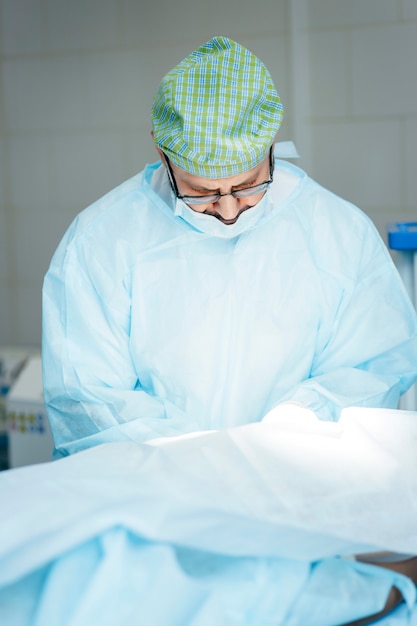 Surgeon performing surgery on breasts in hospital operating room. Surgeon in mask wearing surgical loupes during medical procedure.