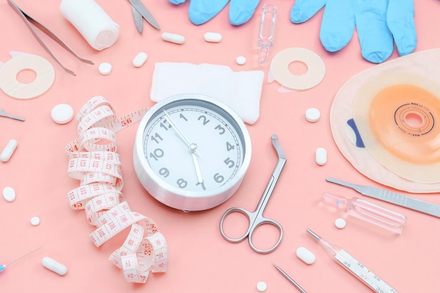 Photo surgeon's kit for surgery with a watch and a colostomy bag on a soft pink background