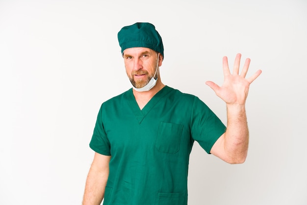 Surgeon senior man isolated on white background smiling cheerful showing number five with fingers.