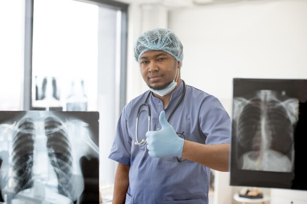 Surgeon showing thumbup on Xray scans background in clinic