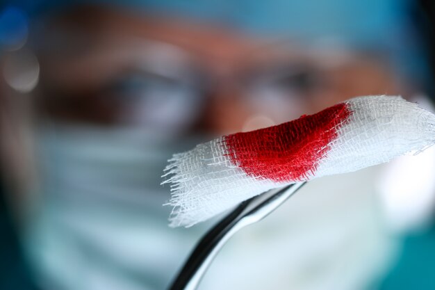 Surgeon in sterile uniform arms holding tools with bio material