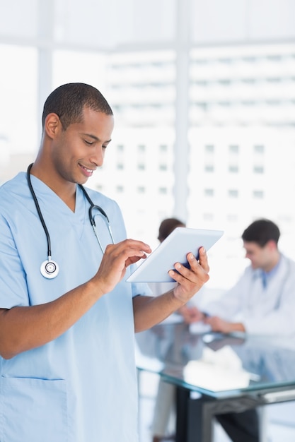 Surgeon using digital tablet with group around table in hospital