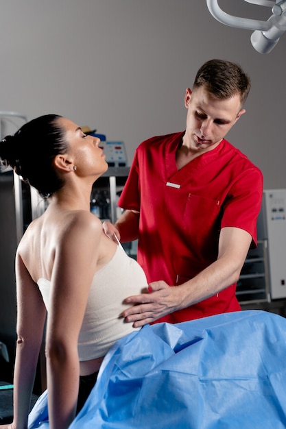 Photo surgeon with woman patient in operating room before breast augmentation for girl. doctor wraps around the patient chest after breast augmentation