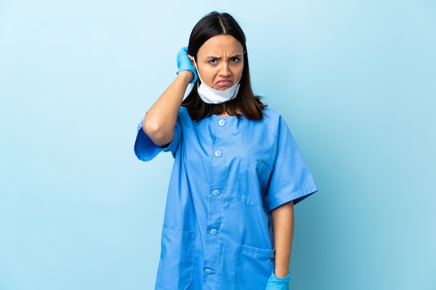 Surgeon woman over blue wall having doubts