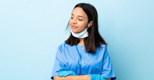 Surgeon woman over blue wall looking to the side