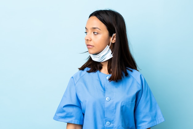 Photo surgeon woman over blue wall looking to the side