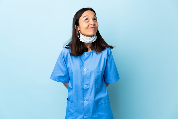 Surgeon woman over blue wall and looking up