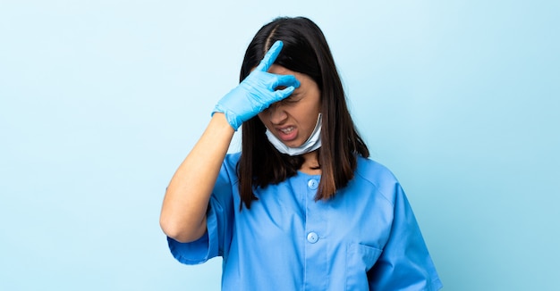 Surgeon woman over blue wall with headache