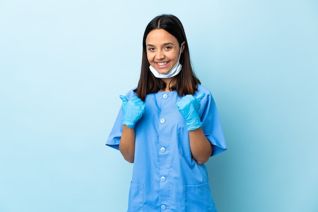 Photo surgeon woman over blue wall with thumbs up gesture and smiling