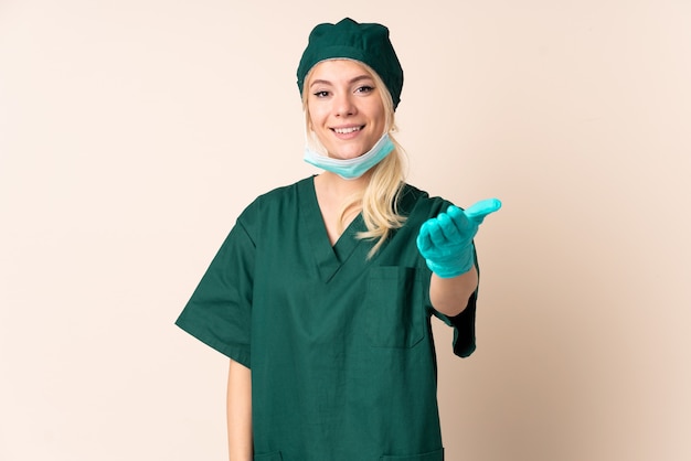 Surgeon woman in green uniform over isolated background handshaking after good deal