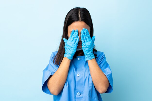 Surgeon woman over isolated blue wall covering eyes by hands