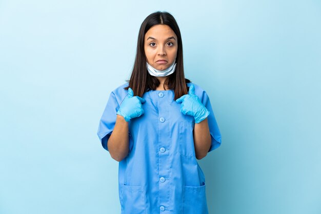 Surgeon woman over isolated blue wall with surprise facial expression