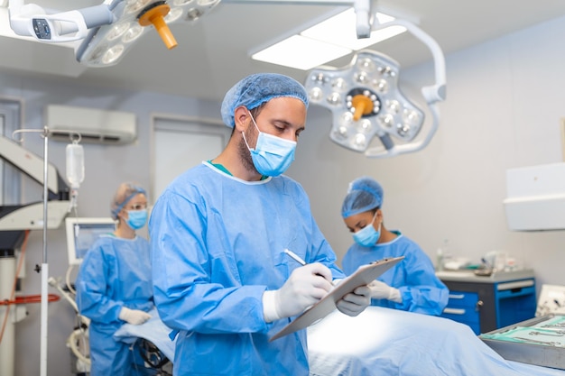 Photo surgeon writing on clipboard in operation room anaesthesiologist writing the updates