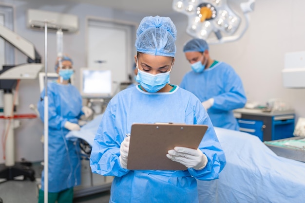 Foto chirurgo che scrive sugli appunti in sala operatoria anestesista che scrive gli aggiornamenti