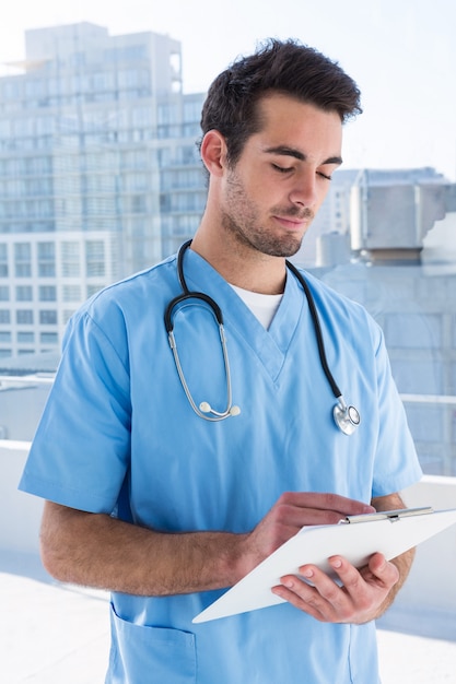 Surgeon writing in clipboard